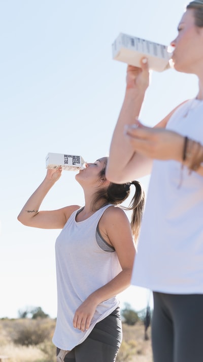 两个女人在锻炼，喝盒装水